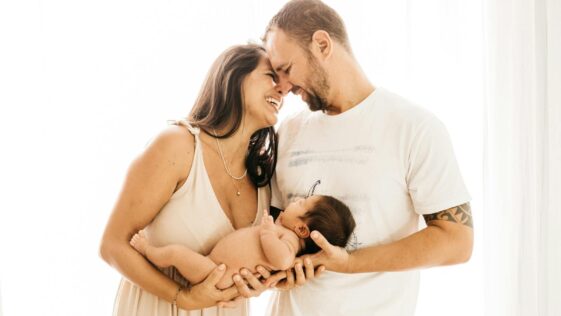 Photo of Laughing Couple Carrying a Baby