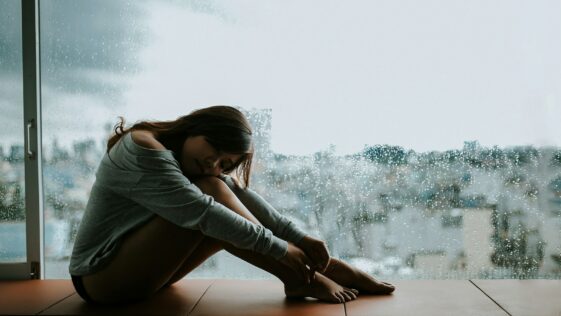 woman in gray long sleeve shirt sitting on window