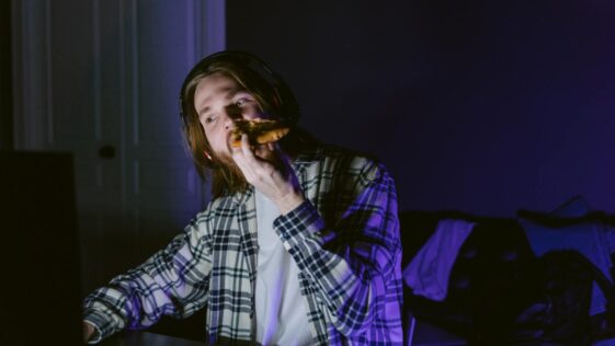 A Man Eating Pizza While in Front of a Computer