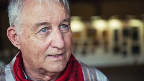 man in red scarf and blue and white plaid shirt