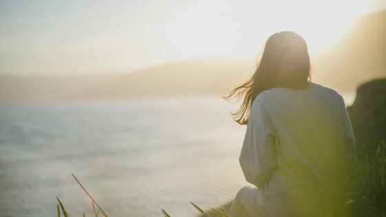 woman wearing gray long-sleeved shirt facing the sea
