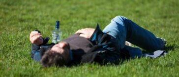 a man laying in the grass with a bottle of beer