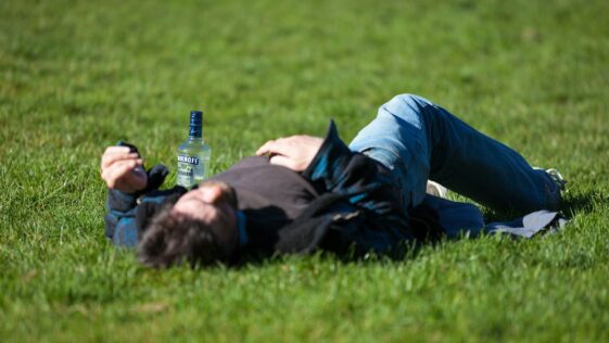 a man laying in the grass with a bottle of beer