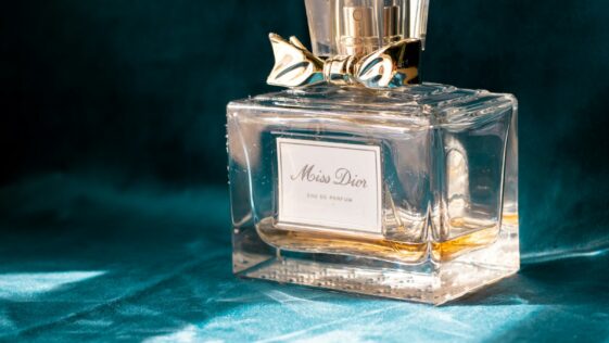 clear glass perfume bottle on blue textile