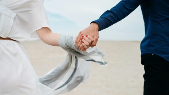 man and woman holding hands together in field during daytime