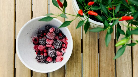 raspberries and black berries in white ceramic bowl