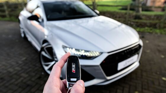 a person holding a car key in front of a silver car