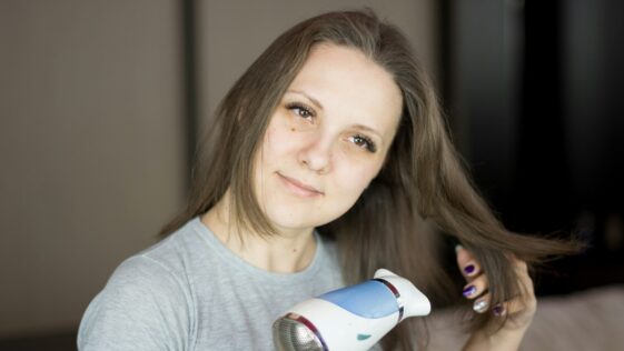 a woman blow drying her hair with a hair dryer