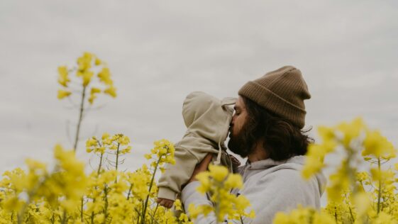 a man and woman kissing in a field of yellow flowers