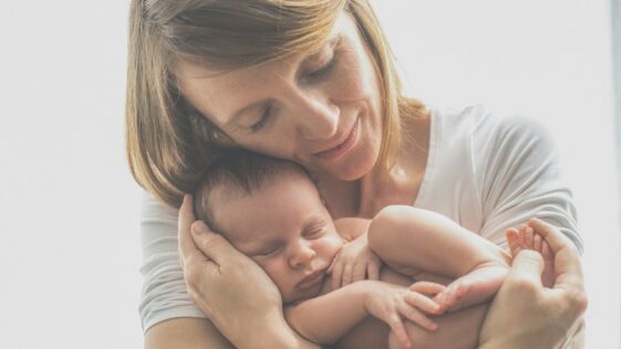 woman in white crew neck t-shirt carrying baby