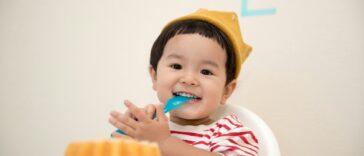 baby sitting on white chair while smiling at the camera