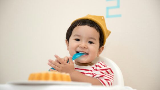 baby sitting on white chair while smiling at the camera
