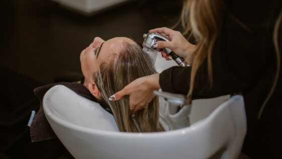 a woman getting her hair cut by a hair stylist
