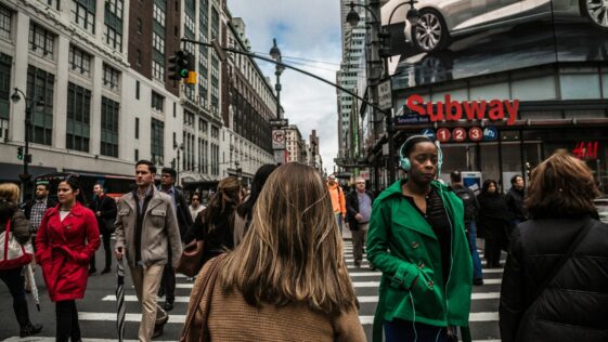 woman wearing green jacket walking on the pedestrian lane during daytime