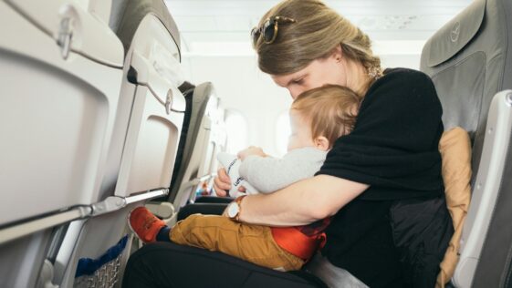 woman carrying baby while sitting on gray seat
