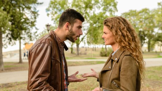 A couple having an argument outdoors, expressing frustration and conflict.