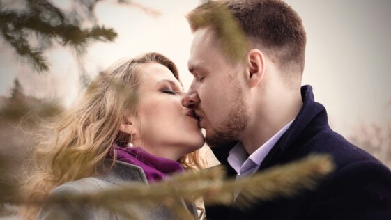 man and woman kissing near green leafed tree