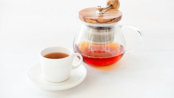 tea on glass teapot beside teacup with saucer