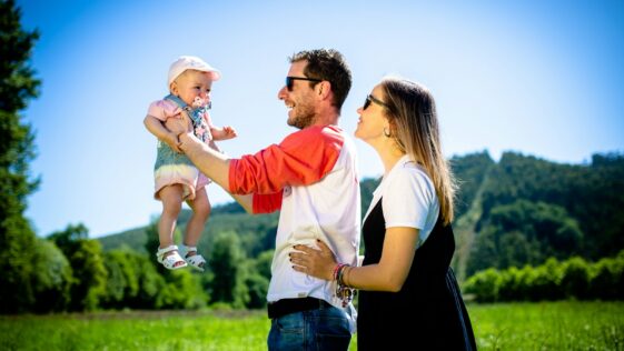 man in white and red polo shirt carrying girl in blue denim jeans during daytime