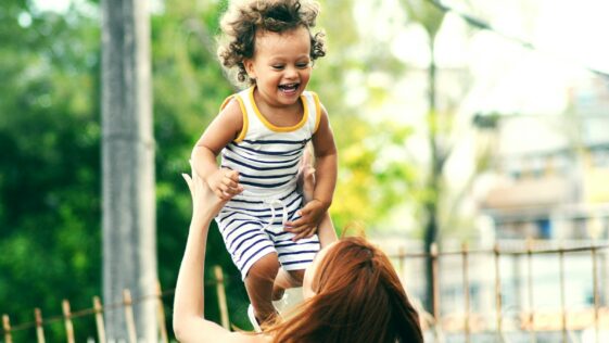 selective focus photo of woman lifting child during daytime