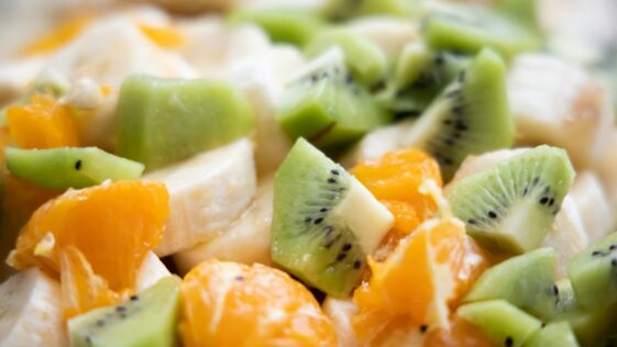 a close up of a fruit salad with kiwi, oranges, and bananas