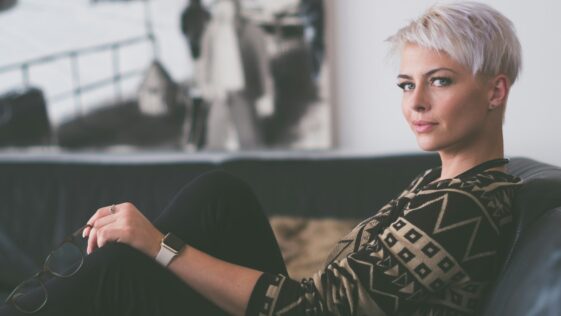 woman sitting on sofa holding eyeglasses
