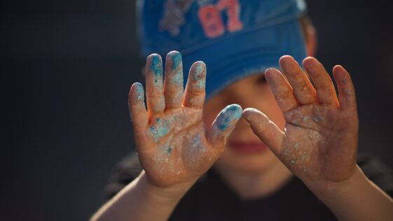 person in blue and white shirt covering face with hands