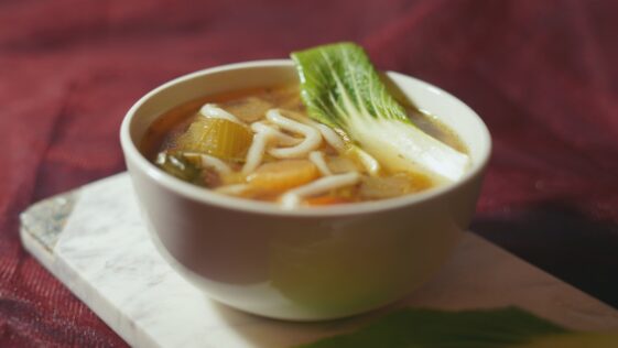 a bowl of soup with noodles, carrots and celery