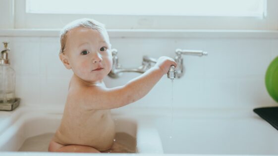 topless baby in bathtub with water