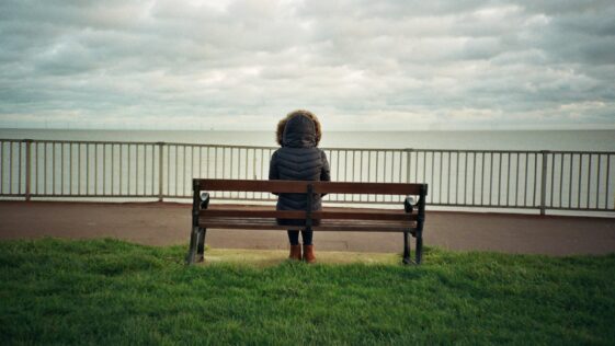woman sitting on brown wooden bench during daytime