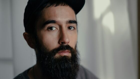 a man with a beard wearing a black hat