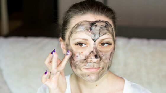 a woman with a face mask on holding her hand up to her face