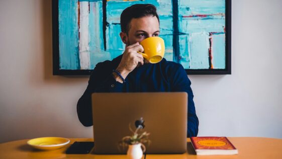 man drinking coffee in front of the laptop computer