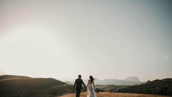 a bride and groom walking on a hill