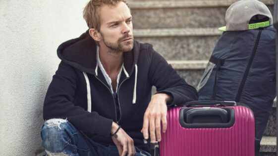 a man sitting next to a purple suitcase