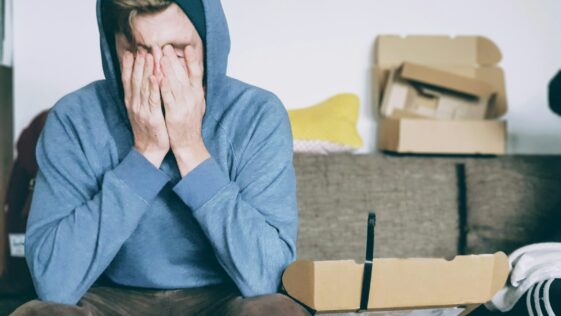 man covering face with both hands while sitting on bench