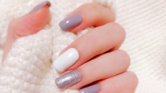 person with pink manicure on white textile