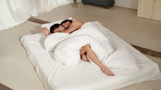 woman lying on bed covered with white blanket