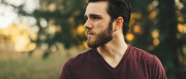 man wearing maroon V-neck t-shirt in forest