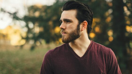 man wearing maroon V-neck t-shirt in forest