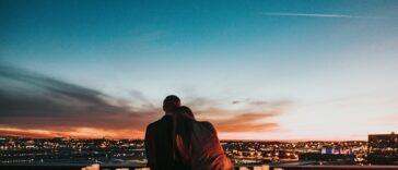 couple sitting on the field facing the city