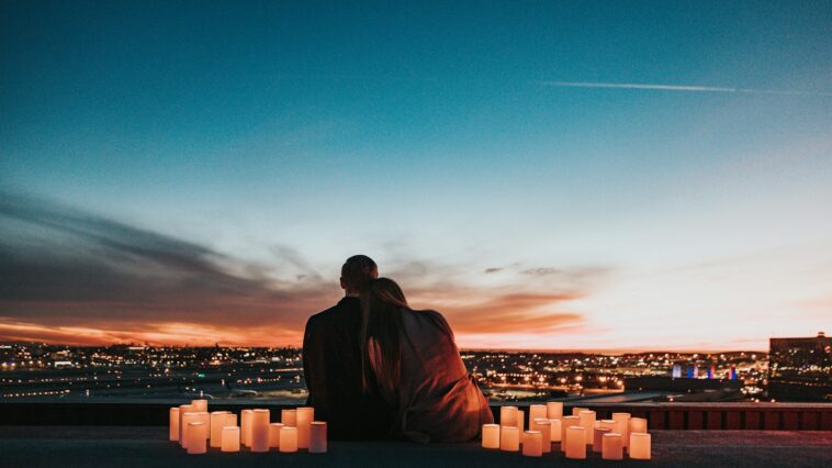 couple sitting on the field facing the city