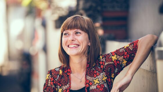 woman in floral-themed cardigan leaning on fence in bokeh photography