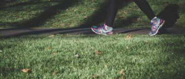 shallow focus photography of person walking on road between grass