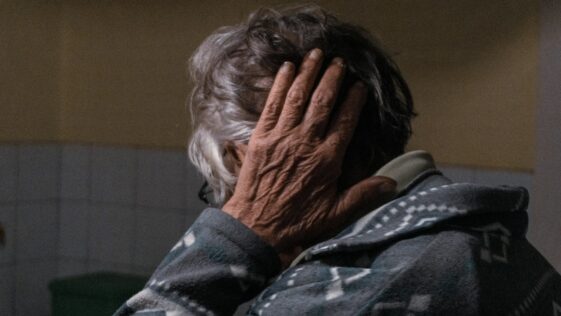 an older woman covering her face with her hands